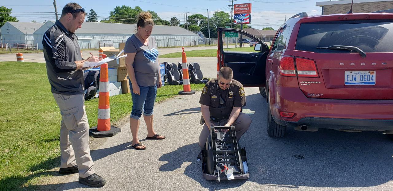Deputy Simon inspects Dawn Dowell's infant car seat with the help of Deputy Hansen. Both are certified child passenger safety technicians who work for the Oceana County Sheriff's Office.